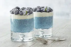 blue chia seed pudding in glasses topped with berries