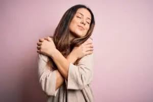 Woman Hugging Herself on Pink Background