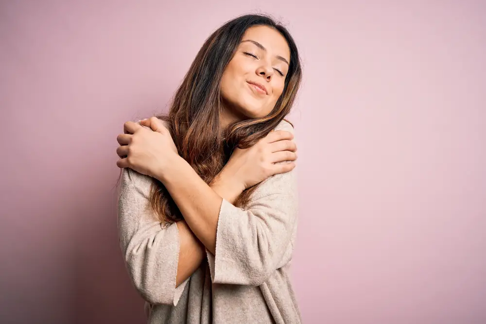 Woman Hugging Herself on Pink Background