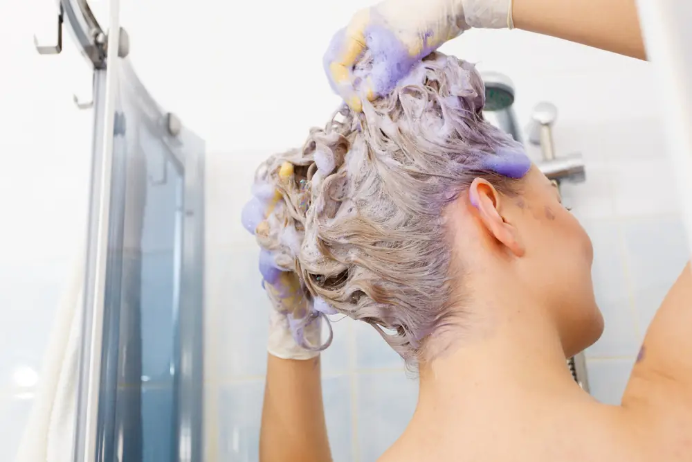 Woman Using Hair Toner on Blonde Hair in Shower