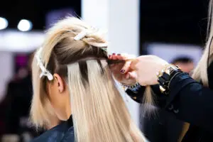 Blonde woman having tape extensions put in hair